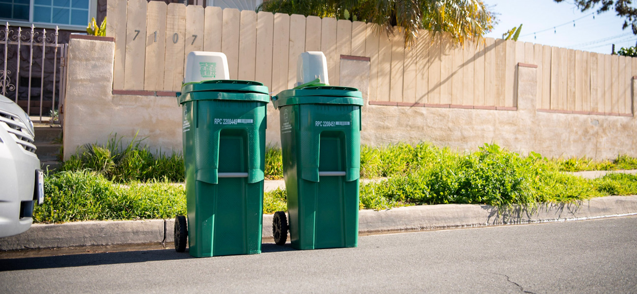 Photo of two green recycling bins next to the curb.