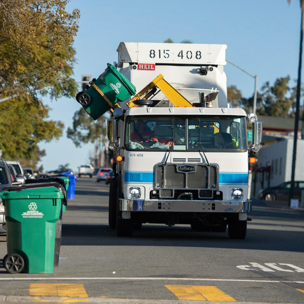 Photo of a garbage truck picking up green recycling bins