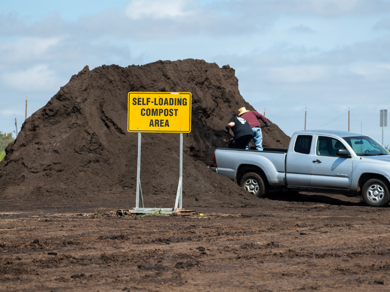 People loading compost into the back of a truck